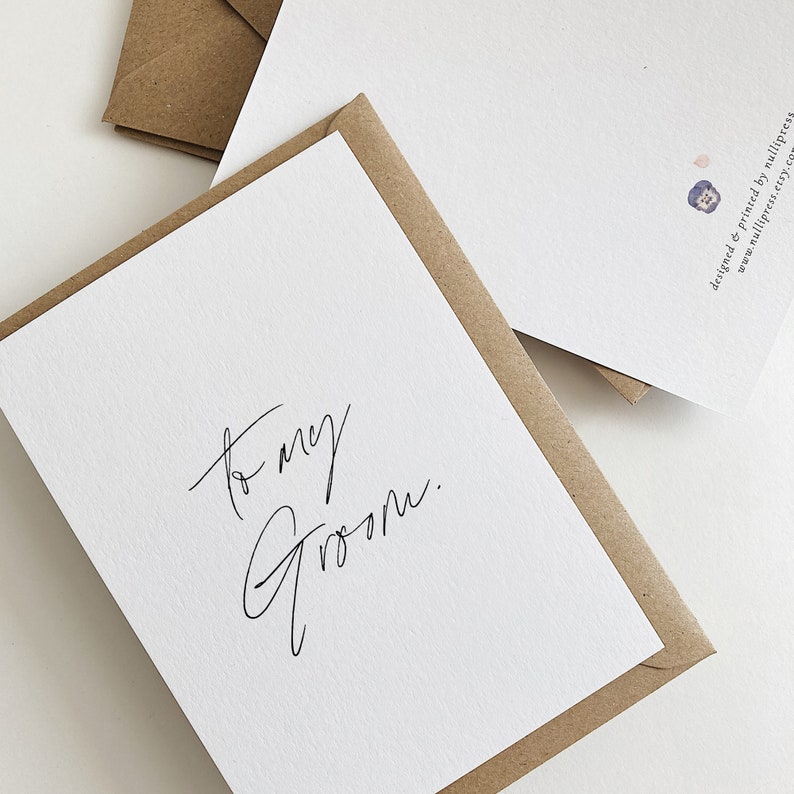 May include: A white card with the text "to my groom." written in black calligraphy.