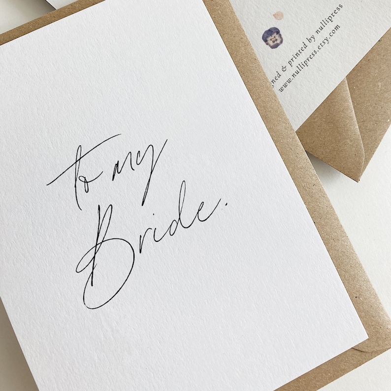 May include: A white card with black calligraphy that reads "to my bride." The card is sitting on a brown envelope.