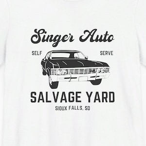 May include: White t-shirt with a black graphic of a vintage car and the text "Singer Auto Salvage Yard Sioux Falls, SD". The design includes the words "Self" and "Serve" on either side of the car.