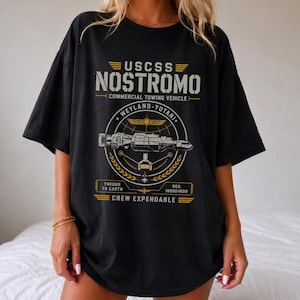Könnte beinhalten: Ein schwarzes Kurzarm-T-Shirt mit einem Grafikdruck des kommerziellen Abschleppfahrzeugs USCSS Nostromo. Das Design enthält den Text USCSS NOSTROMO, WEYLAND-YUTANI, THEDUS TO EARTH, REG. 180924609 und CREW EXPENDABLE in Gelb und Weiß.