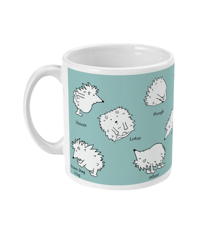 May include: White ceramic mug with a light teal background featuring cartoon hedgehogs in yoga poses. Poses include Dancer, Lotus, Plough, and Wheel. The mug has a white handle and is suitable for hot or cold beverages.