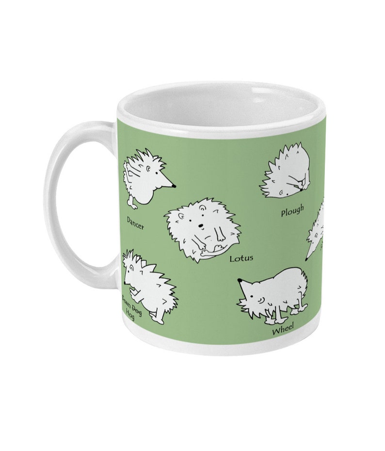 May include: White ceramic mug with a green background featuring cartoon hedgehogs in various poses. The mug has a white handle and the names "Dancer", "Lotus", "Wheel", "Plough", and "Town Dog Hog" are printed near the hedgehogs.