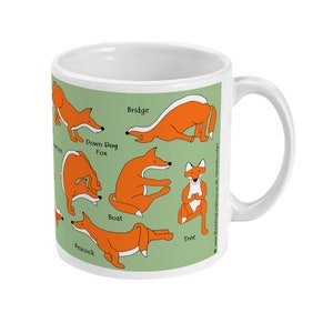 May include: White ceramic mug with a green background featuring illustrations of foxes in various yoga poses. The poses are labeled with the names: Down Dog Fox, Bridge, Boat, Tree, and Peacock. The text "www.BlackDogCreations.co.uk Samantha Lady"