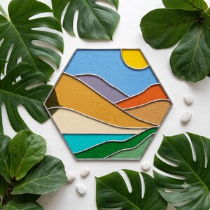 May include: A hexagonal stained glass panel featuring a landscape design with a bright yellow sun, a light blue sky, purple and orange rolling hills, a tan desert area, a turquoise water section, and a vibrant green foreground, all framed in silver metal.
