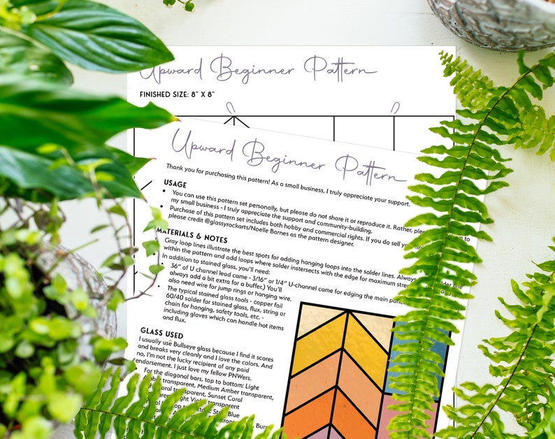 May include: Two sheets of paper with the text "Upward Beginner Pattern" and instructions for a stained glass project. The finished size is 8" x 8". The papers are surrounded by green plants.