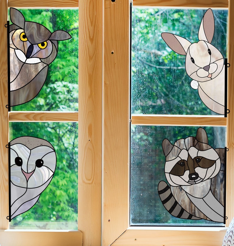 May include: Four stained glass panels depicting a brown owl, a white rabbit, a white owl, and a raccoon. The panels are framed in wood and set against a green leafy background.