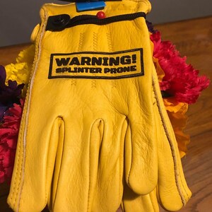 May include: Yellow leather work gloves with a black warning label that reads "WARNING! SPLINTER PRONE".