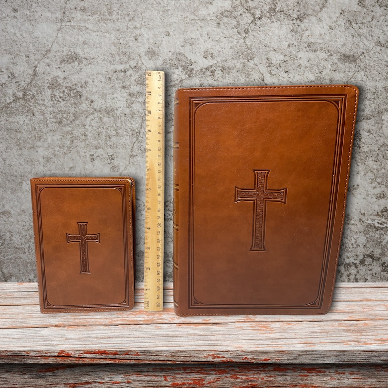 May include: Two brown leather-bound books with a cross embossed on the front cover. The larger book is 11 inches tall and the smaller book is 6 inches tall.