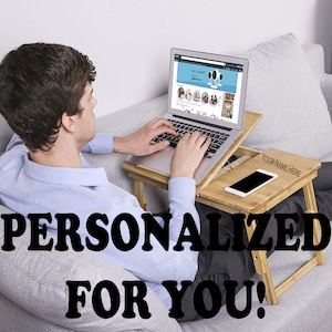 May include: A bamboo laptop desk with a smartphone and a laptop displaying a website. The desk has a slot for a phone and a space for personalization. The text "PERSONALIZED FOR YOU!" is displayed.