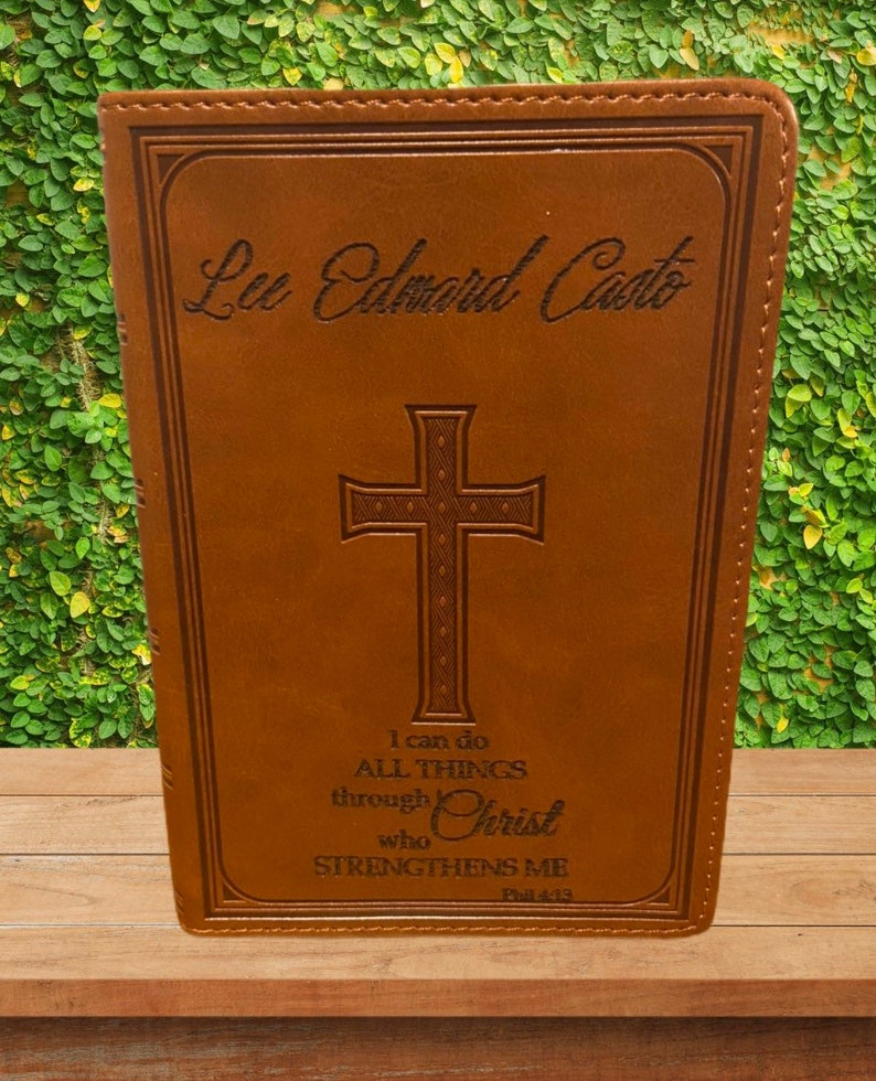 May include: A brown leather-bound journal with a cross and the text "I can do ALL THINGS through Christ who STRENGTHENS ME Phil 4:33" engraved on the front. The name "Lee Edward Casto" is also engraved on the front.