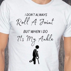 May include: White t-shirt with black text that reads "I don't always roll a joint but when I do it's my ankle". A black stick figure with a crutch and a bandage on their leg is below the text.