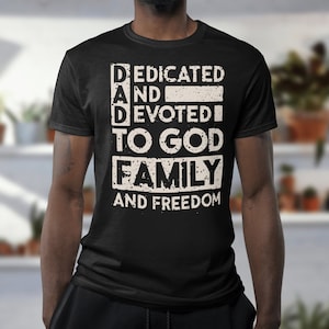 May include: Black t-shirt with a white graphic that reads "Dedicated and Devoted to God Family and Freedom".