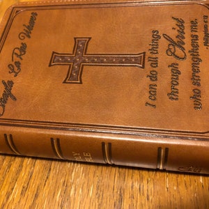 May include: A brown leather-bound Bible with a gold cross and the inscription "I can do all things through Christ who strengthens me. -Philippians 4:13".