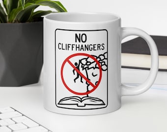 May include: A white ceramic mug featuring a black graphic design of an open book and a stick figure hanging from a cliff edge, crossed out by a red circle. The text above the graphic reads NO CLIFFHANGERS in bold black capital letters.