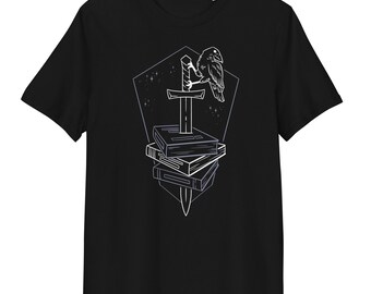 May include: A black short-sleeved t-shirt featuring a white line art graphic on the chest. The design depicts a raven perched on a sword that is driven through a stack of three books, all set against a pentagonal background with small stars.