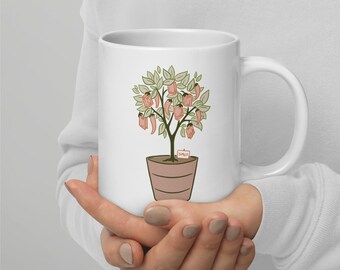 May include: A white ceramic mug featuring a graphic illustration of a potted plant with green leaves, red chilli peppers, and small rectangular orange books hanging from the branches. A small white sign at the base of the plant reads SMUT.