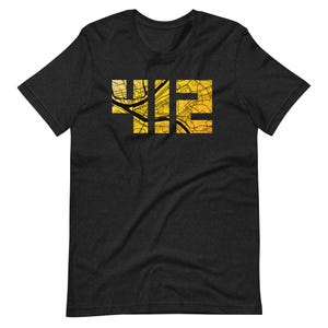 May include: A charcoal grey short-sleeve t-shirt featuring the number 412 printed in a bold, block font. The interior of the numbers is filled with a detailed, golden-yellow street map graphic that shows various roads and city grid lines.
