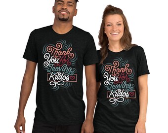 May include: A charcoal grey short-sleeve t-shirt featuring a graphic design with the text Thank You for Leaving Kudos in white, red, and teal cursive lettering, accented by swirling patterns and a small red heart inside a rectangular border.