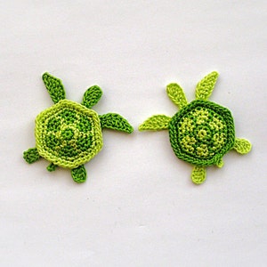 May include: Two crocheted green and light green sea turtles on a white background.