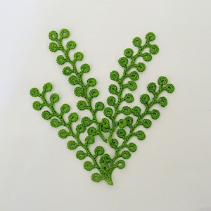 May include: Green crocheted fern-like plant with multiple stems and curled leaves.