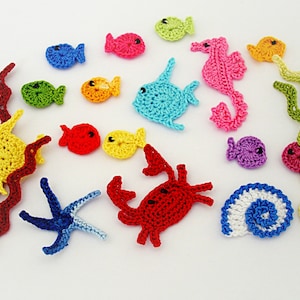 May include: A collection of crocheted sea creatures and seaweed, including a yellow fish, red crab, blue starfish, pink seahorse, and green seaweed.