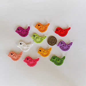 Peut inclure: Dix formes d'oiseaux en crochet de différentes couleurs, dont le violet, le blanc, l'orange, le vert et le rouge. Les oiseaux sont à peu près de la taille d'une pièce de dix centimes d'euro.