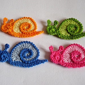 May include: Four crocheted snail ornaments in different colors: orange and yellow, green, blue and white, and pink and white.