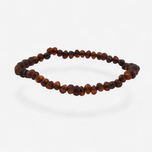 May include: A dark brown beaded bracelet. The beads are small, round, and vary in shade from light to dark brown. The bracelet is displayed on a white background.