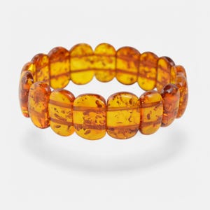 Könnte beinhalten: Ein Armband aus Bernsteinperlen. Die Perlen sind in einem satten, warmen Bernsteinton gehalten und oval geformt. Das Armband besteht aus einer einzigen Perlenkette und ist so konzipiert, dass es bequem am Handgelenk sitzt.