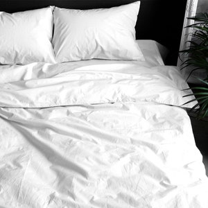 Puede incluir: Una cama con ropa de cama blanca. Dos almohadas mullidas descansan sobre la cama, junto con una funda n&oacute;rdica y s&aacute;banas blancas. La tela parece suave y la impresi&oacute;n general es de un dormitorio limpio y fresco.