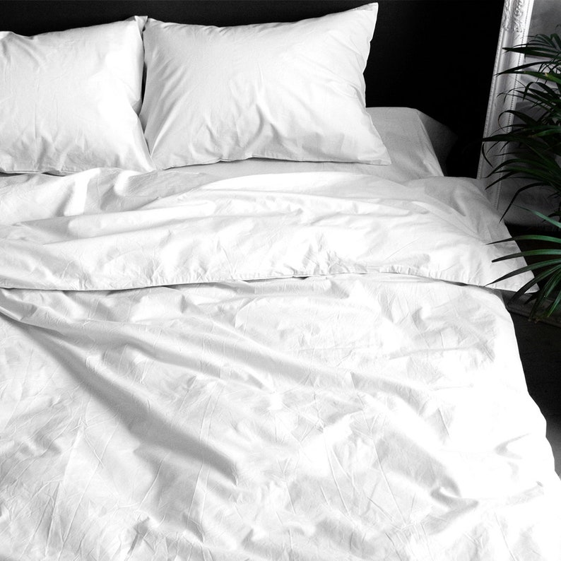 Puede incluir: Una cama con ropa de cama blanca. Dos almohadas mullidas descansan sobre la cama, junto con una funda n&oacute;rdica y s&aacute;banas blancas. La tela parece suave y la impresi&oacute;n general es de un dormitorio limpio y fresco.