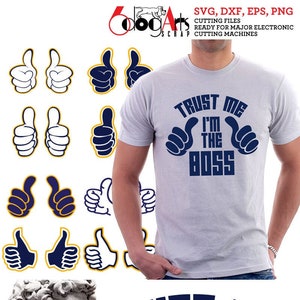 May include: A light gray t-shirt with the text "TRUST ME I'M THE BOSS" in navy blue. The design includes thumbs-up hand gestures. Also shown are thumbs-up graphics and a blue t-shirt with the same design.