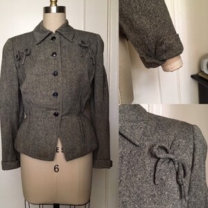 May include: A gray tweed jacket with a button-up front and a fitted waist. The jacket has a collar and long sleeves with cuffs. There are decorative bows on the shoulders and at the front of the jacket.