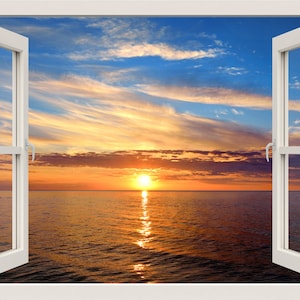 Puede incluir: Una ventana blanca abierta enmarca una puesta de sol sobre el mar. El cielo es una mezcla de azul, naranja y amarillo, con el reflejo del sol en el agua. La ventana abierta invita a disfrutar de la tranquila escena.