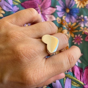 K&ouml;nnte beinhalten: Ein silberner Ring in Herzform an einem Finger.