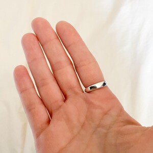 K&ouml;nnte beinhalten: Ein silberner Bandring an einem Finger.