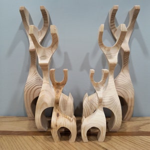 May include: A set of seven wooden reindeer figurines in various sizes, all made of light brown wood. The reindeer are arranged in a row, with the largest reindeer in the back and the smallest reindeer in the front.