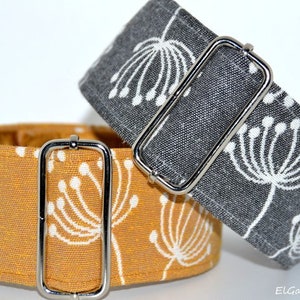 Puede incluir: Dos collares para perros con estampados florales. Uno es amarillo mostaza con flores blancas, el otro es gris con flores blancas. Ambos tienen herrajes metálicos plateados.