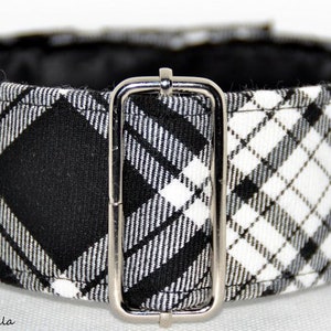 May include: A black and white checked dog collar with a silver-coloured metal buckle. The collar has a classic pattern and a black interior lining. The fabric is woven, and the collar is adjustable.