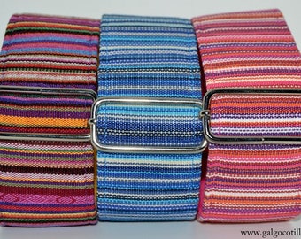 Puede incluir: Tres cinturones de tela tejida colorida con hebillas rectangulares plateadas. Los cinturones presentan rayas horizontales en tonos morado, naranja, rosa, azul y blanco. Los cinturones se muestran uno al lado del otro.