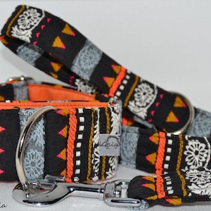 Puede incluir: Juego de collar y correa para perros con un patrón geométrico negro, naranja y amarillo. El collar tiene una hebilla de metal plateado y una correa a juego. El conjunto es para mascotas.