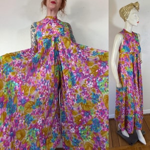 May include: A vintage floral print jumpsuit in shades of pink, blue, and yellow. The sleeveless jumpsuit features a high neckline and a wide-leg design. The fabric is adorned with a vibrant floral pattern, creating a retro aesthetic.