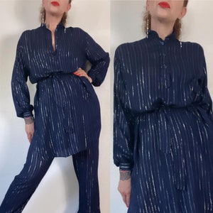 May include: A navy blue two-piece outfit with vertical silver stripes. The long-sleeved top has a mandarin collar and a matching belt. The pants are straight-legged. The outfit is made of a lightweight fabric.