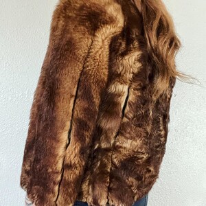 May include: A brown faux fur jacket with a shawl collar. The jacket is made of a soft, plush fabric and has a relaxed fit.