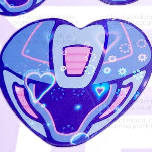 Puede incluir: Varias pegatinas en forma de corazón con un diseño futurista. Las pegatinas presentan un degradado de azul y morado, con acentos rosas y blancos. Cada corazón tiene una forma rectangular central y un diseño en forma de corazón en el centro.