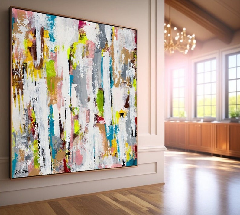 May include: Abstract painting with bold strokes of white, gray, blue, yellow, pink, and brown. The painting is framed in a thin, gold-colored frame.