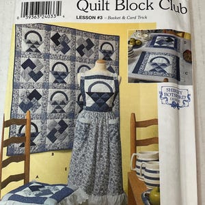 Puede incluir: Patrón de Simplicity Quilt Block Club. El paquete presenta un edredón, un delantal y un cojín para silla con un diseño de cesta azul y blanco. El patrón incluye la lección #3, "Basket & Card Trick". El paquete está etiquetado como "Talla única".