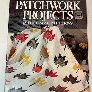 以下が含まれることがあります： 「パッチワーク・プロジェクト」というタイトルの、ベターホームズアンドガーデンズの書籍。表紙には、赤、オレンジ、黄色、茶色の秋葉の組み合わせでパッチワーク模様が施されたキルトが描かれている。