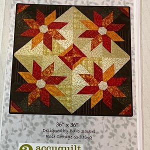 May include: A quilt pattern titled "Aspen in Bloom" featuring a floral design with red, orange, and gold fabrics. The quilt measures 36 x 36 inches. Designed by Barb Sackel for Rose Cottage Quilting. Accuquilt GO! compatible.