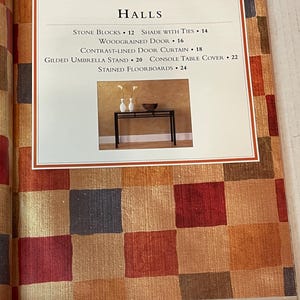 May include: A black metal console table with a wood-grain background. The table has a rectangular top and a lower shelf. The table is decorated with two small white vases and a bowl. The text "HALLS" is at the top of the image with a list of items and their prices.